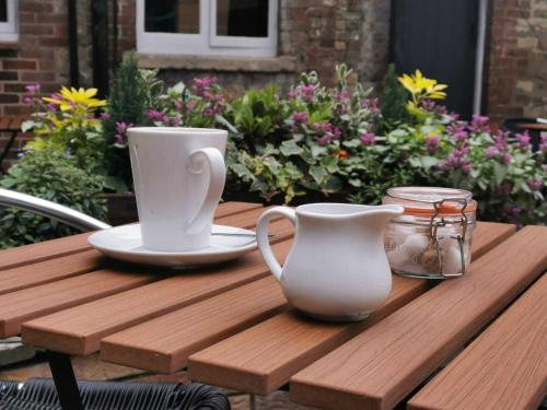 a wooden table with two cups and a vase on it at The Old Bell - Warminster in Warminster