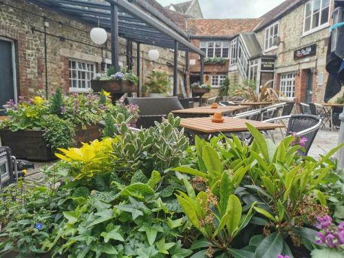 a patio with flowers and tables and chairs at The Old Bell - Warminster in Warminster