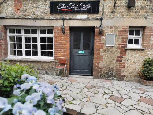 a brick building with a black door and a chair at The Old Bell - Warminster in Warminster