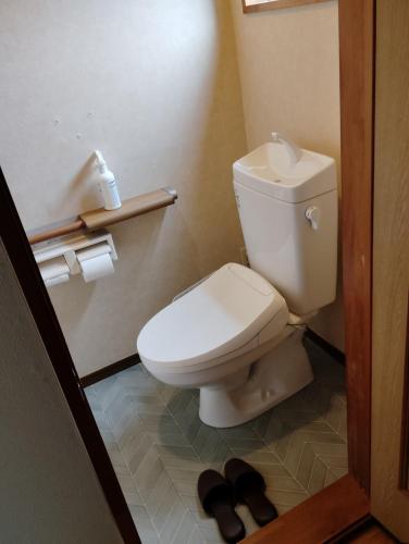 a bathroom with a toilet and a pair of shoes at Guesthouse MARU 1日1組 貸切の民泊 丸 ファミリー グループ向け民家の宿 Vintage House, Parking, Free Wifi, Smoke free in Ishinomaki