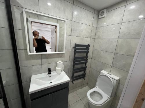 a person taking a picture of a bathroom with a toilet at Modern en-suite rooms Luton air port in Luton