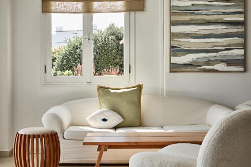 a living room with a white couch and a window at Paros Agnanti Resort & Spa in Parikia