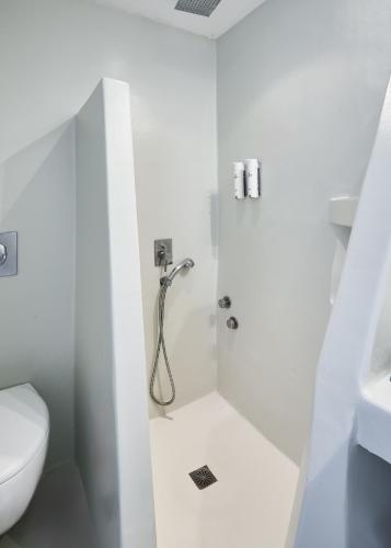 a white bathroom with a shower and a toilet at Paros Agnanti Resort & Spa in Parikia