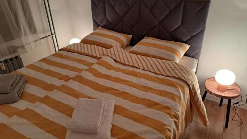 a bed with an orange and white striped blanket at Apartman 19 Vinkovci, klimatiziran, self check-in in Vinkovci