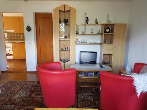 a living room with red chairs and a desk with a laptop at Schweizer Haus in Sarnen