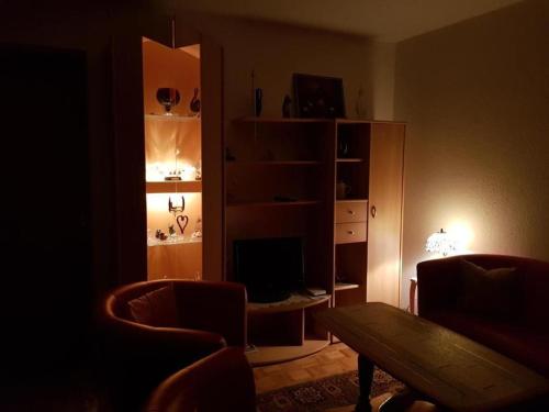 a dark living room with a table and a shelf with a television at Schweizer Haus in Sarnen