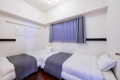a bedroom with two beds and a window at Flowing home in Nagoya