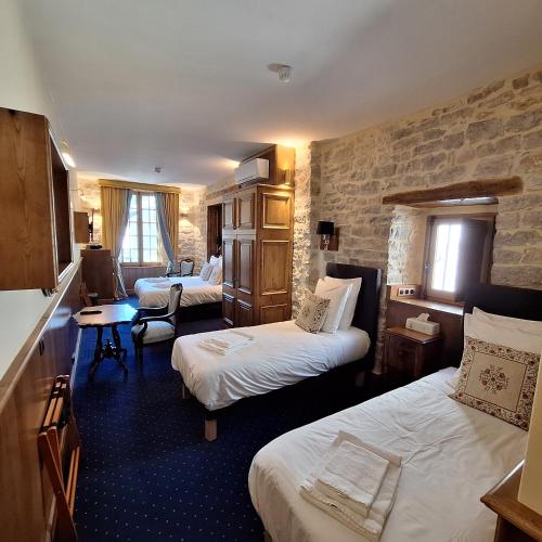 a hotel room with two beds and a chair at Hôtel-Restaurant Le Manoir De Montesquiou in La Malène
