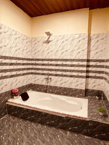 La salle de bains est pourvue d'une baignoire et de papier peint noir et blanc. dans l'établissement Hotel BR Palace, à Hyderabad