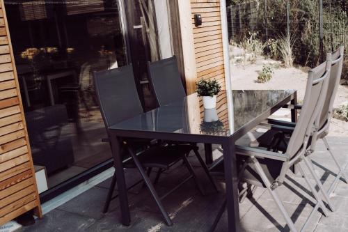 a glass table and two chairs on a patio at Tiny House 1 Strandperle in Freest