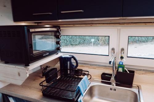 a kitchen with a sink and a microwave at Tiny House 2 Dünenblick in Freest