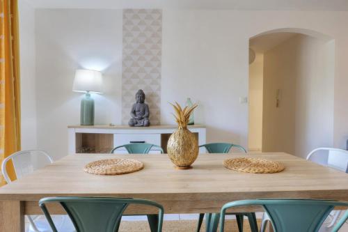 a dining room table with green chairs and a vase on it at Apt Le Sunny - T4 Boucan Canot in Saint-Paul