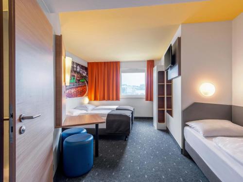 a hotel room with two beds and a desk at B&B Hotel Augsburg-Süd in Augsburg