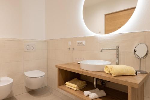 a bathroom with a sink and a toilet and a mirror at Pension Kleon in Rifiano