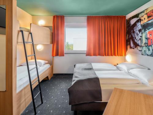 a bedroom with two bunk beds and a window at B&B Hotel Mainz-Hechtsheim in Mainz