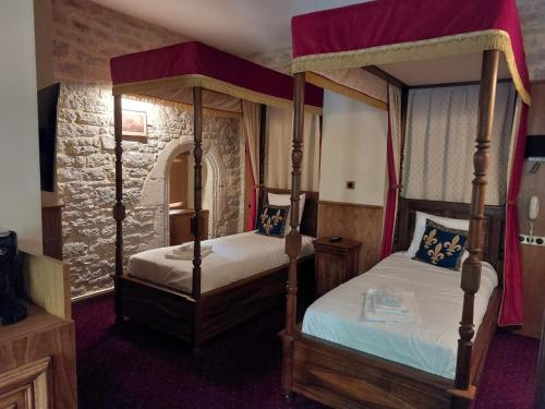 two beds in a room with two canopy beds at Hôtel-Restaurant Le Manoir De Montesquiou in La Malène