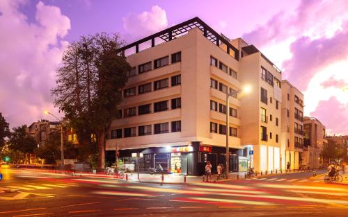 a large white building on a city street at night at Iconic Hotel in Tel Aviv