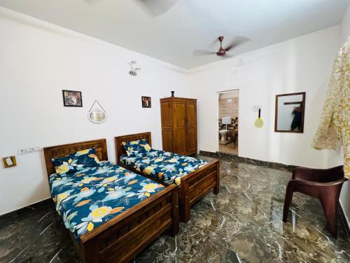 a bedroom with two beds and a chair at THEE Confort rooms in Pondicherry