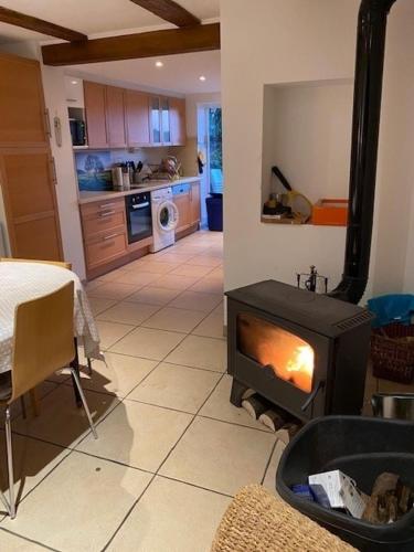 a kitchen with a stove in the middle of a room at Petit coin de bonheur - 3 chambres & 1 poele à bois in Hultehouse