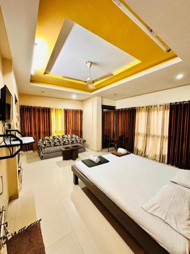 a bedroom with a large bed and a living room at Hotel Diamond Executive in Solapur