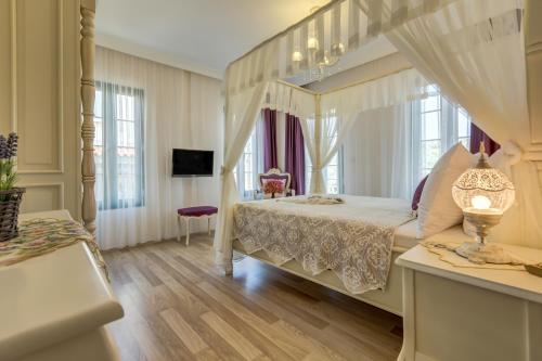a bedroom with a canopy bed and a television at Cunda Esen Hotel in Ayvalık