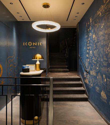 a hallway with blue walls and stairs with a chandelier at Iconic Hotel in Tel Aviv