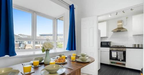 a kitchen with a table with food and orange juice at Iron House - Sleeps 11 - For Contractors & Families - Free Parking - Near Excel , Canary Wharf, O2, City AirPort & GreenWich in London