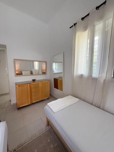 a white bedroom with a bed and a mirror at Villa Ryma in Kelibia Center in Kelibia