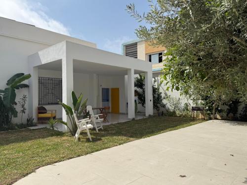 a white house with a chair in the yard at Villa Ryma in Kelibia Center in Kelibia