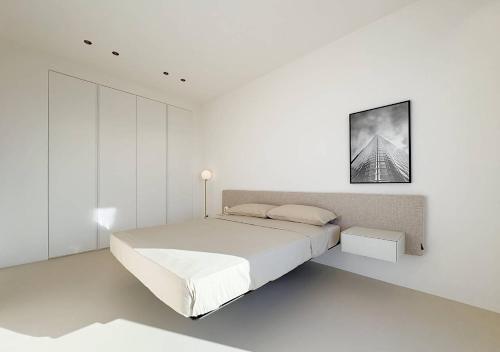 a white bedroom with a bed and a picture on the wall at Solemar Sicilia - Villa Gloria in Ficarazzi