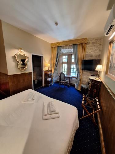 a hotel room with a large bed and a desk at Hôtel-Restaurant Le Manoir De Montesquiou in La Malène