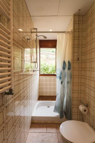 a bathroom with a tub and a toilet and a window at Masia Boutique con Infinity Pool in Calvinyá