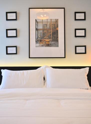 a bedroom with a white bed with framed pictures on the wall at Bazaar Inn Hotel in Tirana