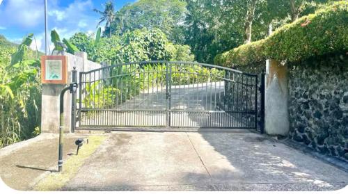 a metal gate on a stone wall with a street at Ngermid Oasis-Spacious Studio With Kitchenette & Scenic Views in Koror