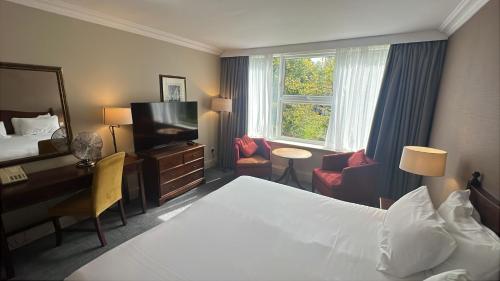 a hotel room with a bed and a desk and a television at Winchester Cathedral View By Dancenter in Winchester