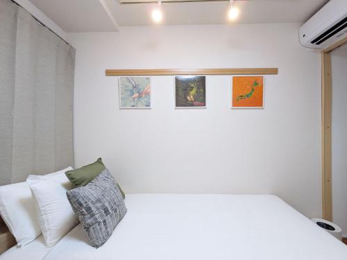 a bedroom with a white bed and some pictures on the wall at Laze Nakano 2bed Travel Work Broadway in Tokyo