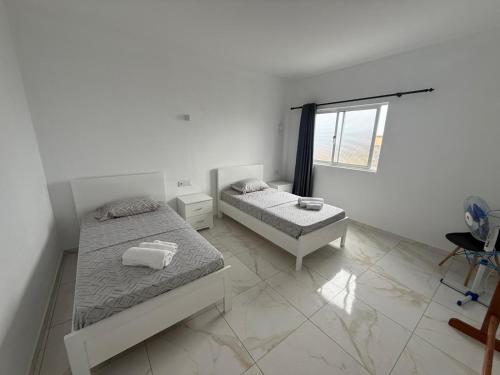 a bedroom with two beds and a window at MeloMar Rooms in Ponta do Sol
