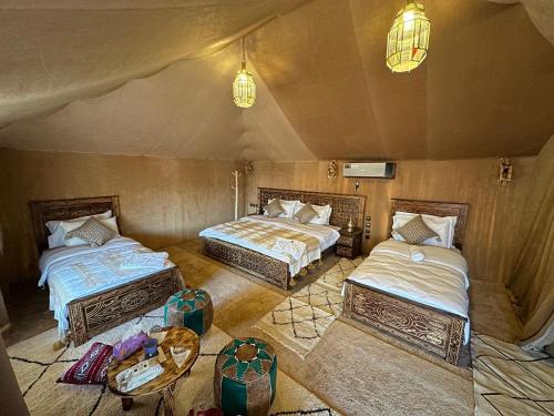 een kamer met twee bedden en een tafel en twee lampen bij Morocco Luxury Desert Camp in Merzouga