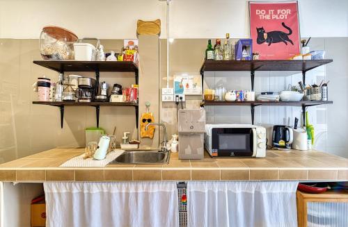 a kitchen counter with a sink and a microwave at Cat House BKK in Bangkok