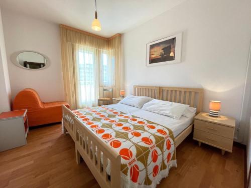 a bedroom with a bed with an orange chair at Cozy flat with shared pool in Porto Santa Margherita di Caorle