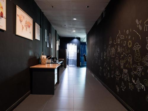 a hallway with a black wall with drawings on it at Capsule inn CI enterprise in Kota Kinabalu