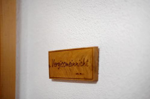 a woodenswitch on a white wall with writing on it at Ruhbauernhof in Kirchzarten