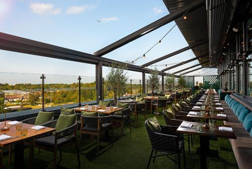 - un restaurant avec de longues tables, des chaises et des fenêtres dans l'établissement Carlton Hotel Dublin Airport, à Cloghran