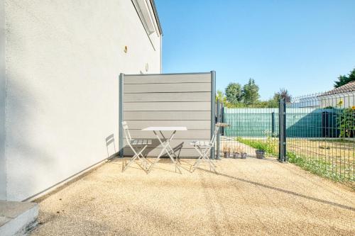 a table and two chairs sitting next to a fence at Nid tranquille in Trélissac