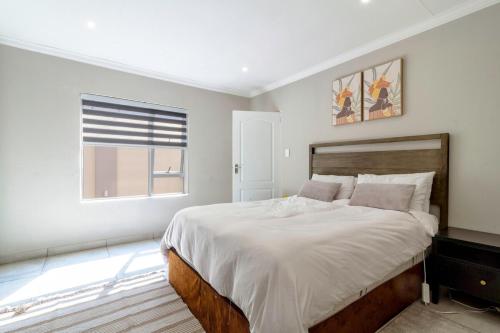 ein weißes Schlafzimmer mit einem großen Bett und einem Fenster in der Unterkunft #AlimamaSpaces Culross Cottage Retreat in Johannesburg