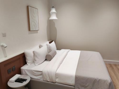 a bedroom with a large bed with white sheets and pillows at Baithans 24 Furnished Apartments Hotel LLC in Ajman 