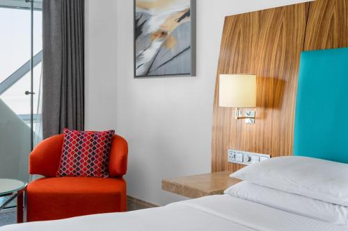 a hotel room with a bed and a red chair at Andaz Capital Gate Abu Dhabi, By Hyatt in Abu Dhabi