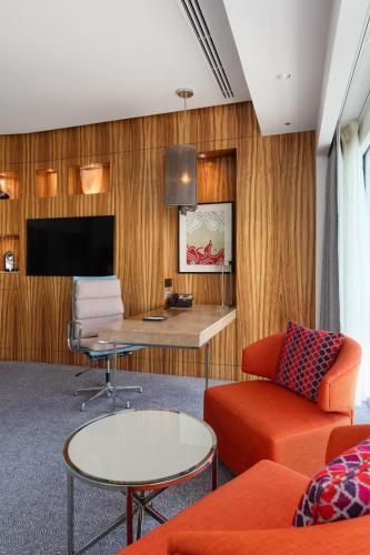 a living room with orange furniture and a flat screen tv at Andaz Capital Gate Abu Dhabi, By Hyatt in Abu Dhabi