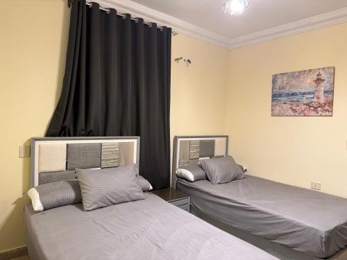 a bedroom with two beds and a window with black curtains at شاليه بقرية كورال هيلز الساحل الشمالي برأس الحكمة in Jalāl
