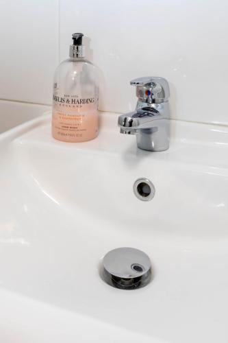 a soap bottle sitting on a bathroom sink at Charming Peaceful 2 Bedroom with Parking and Garden in London